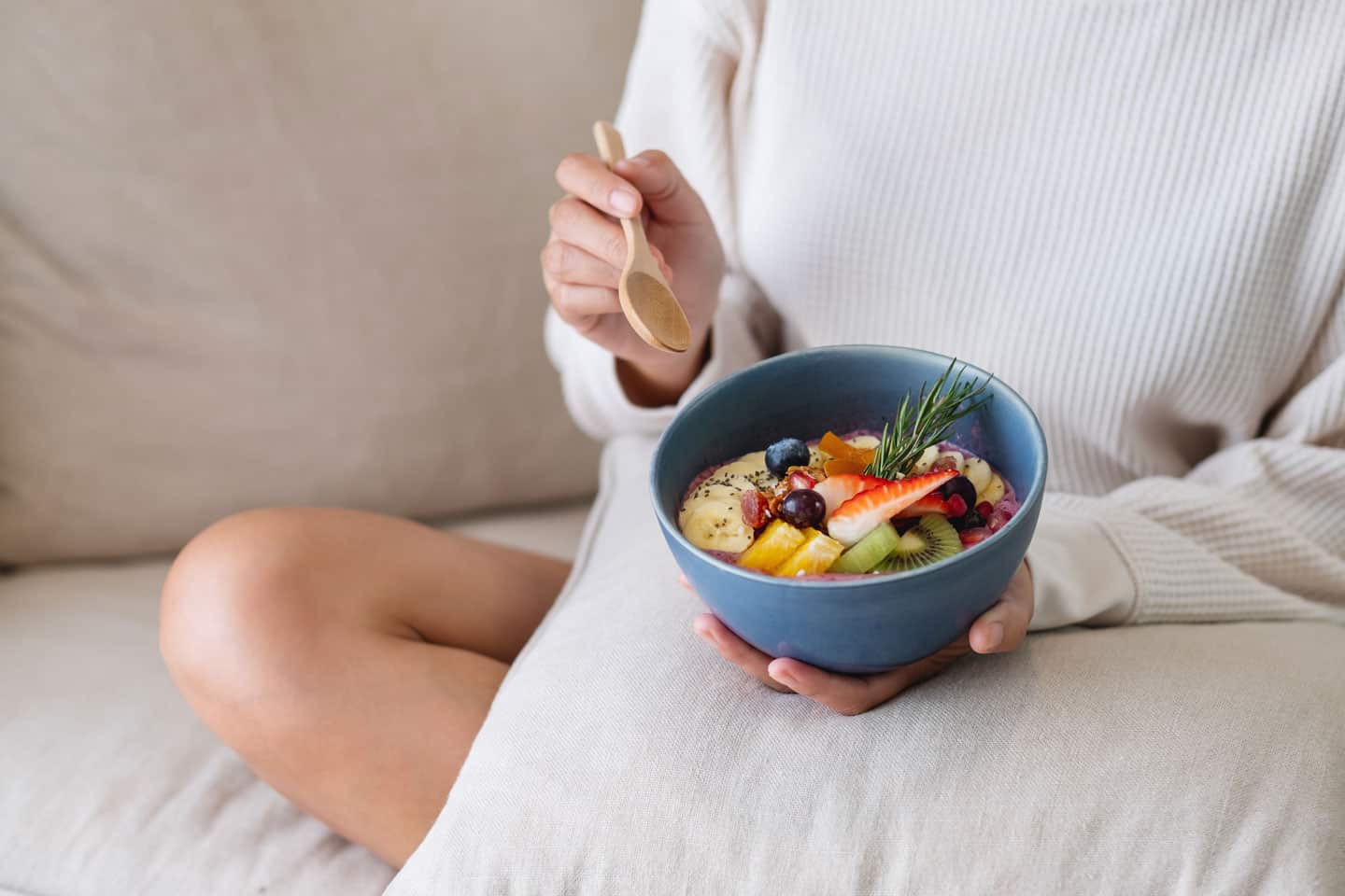 a woman eating healthy blueberry smoothie bowl